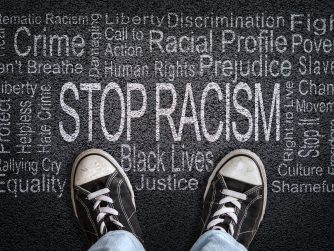 Stop Racism written on black top with sneakers in image
