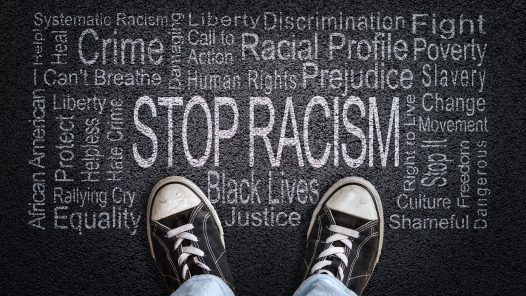 Stop Racism written on black top with sneakers in image