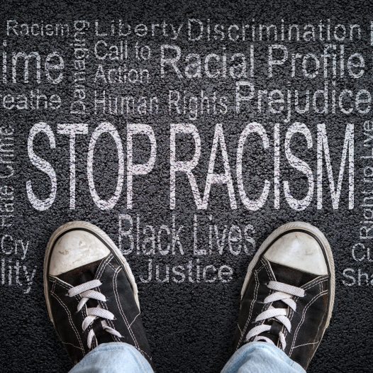 Stop Racism written on black top with sneakers in image