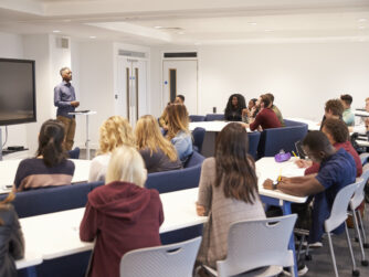 University students study in a classroom with African American male lecturer