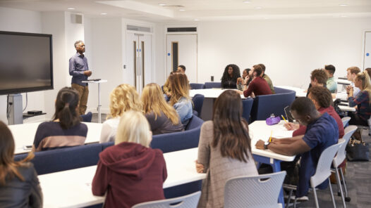 University students study in a classroom with African American male lecturer