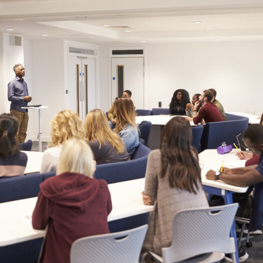 University students study in a classroom with African American male lecturer