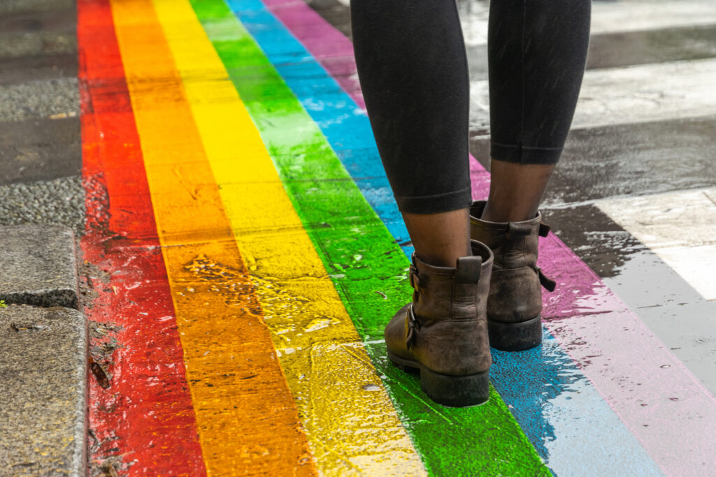 Female legs walking on rainbow crosswalk in pride parade.