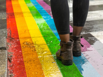 Female legs walking on rainbow crosswalk in pride parade.