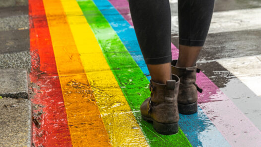 Female legs walking on rainbow crosswalk in pride parade.