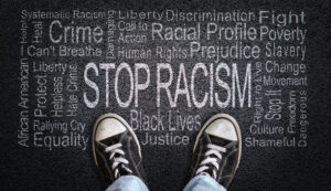 Person standing over Stop Racism word cloud.