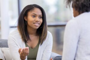 Teenage girl gestures while talking with a female therapist.