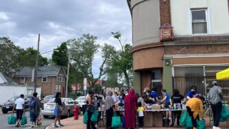 Street corner in city of Buffalo. People lining up at tables for food distribution.