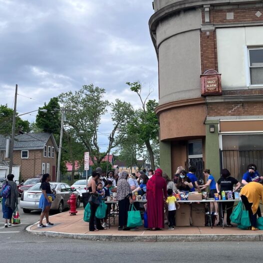 Street corner in city of Buffalo. People lining up at tables for food distribution.