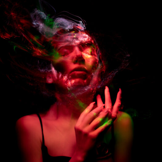 Psychedelic woman with eyes closed and colored hair melting into the background.
