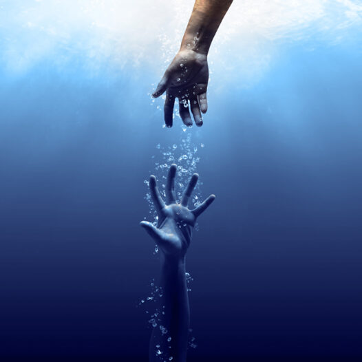 Hand reaching down into the water to grab the out stretched arm of someone sinking in the water.