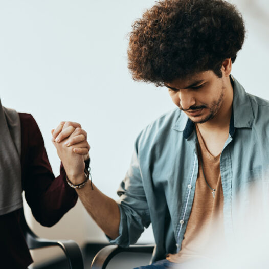 Man holding hands in prayer with woman in head scarf.