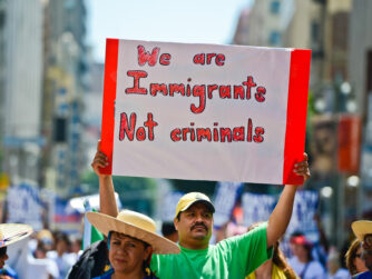 Protesters with Hispanic male holding a sign saying we are Immigrants not criminals