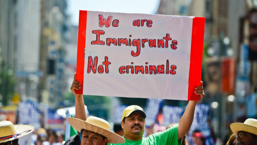 Protesters with Hispanic male holding a sign saying we are Immigrants not criminals
