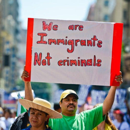 Protesters with Hispanic male holding a sign saying we are Immigrants not criminals