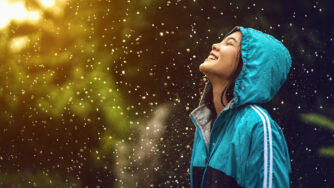 Woman standing in the rain looking up smiling with joy.