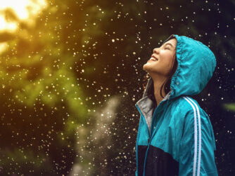 Woman standing in the rain looking up smiling with joy.