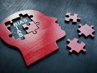 Cut out shape of a head with puzzle pieces missing from the mind. With bias written to indicate the bias of mental health diagnosis.