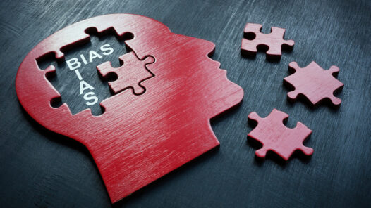 Cut out shape of a head with puzzle pieces missing from the mind. With bias written to indicate the bias of mental health diagnosis.