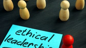 Ethical Leadership written on a sticky note surrounded by white pegs with one red peg standing out from the crowd.