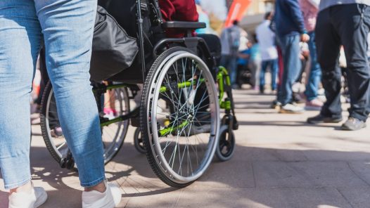Person in wheelchair trying to navigate through a crowd.
